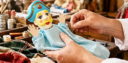 Vestizione artigianale di un burattino con costumi cuciti a mano